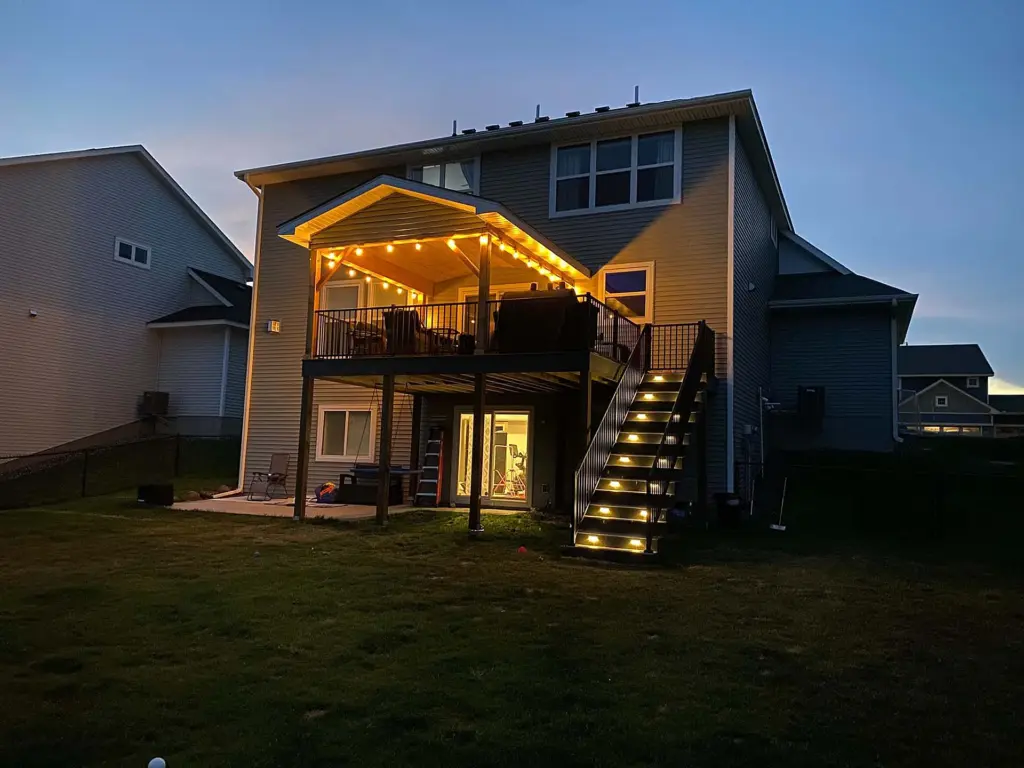 elevated-deck-with-lights-on-stairs-and-black-metal-railings-with-outdoor-living-space-on-the-porch-in-twin-cities-mn