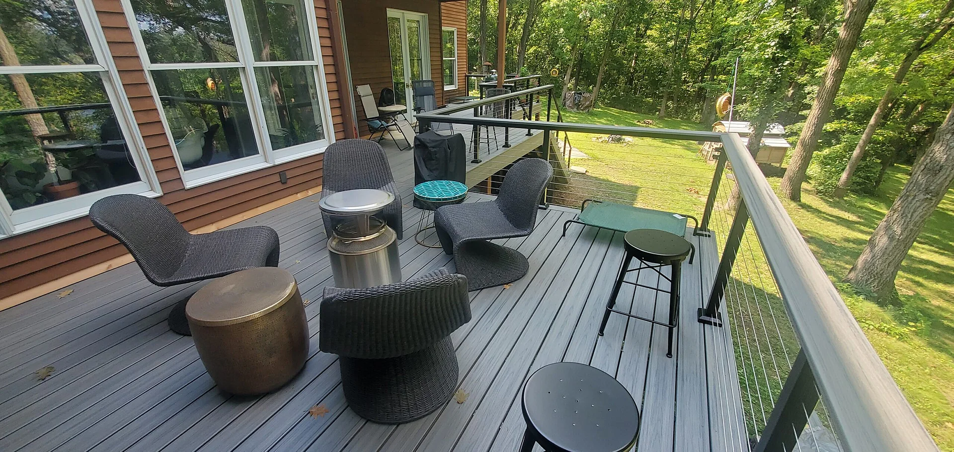 gray-commercial-deck-with-cable-railing-and-outdoor-chairs-and-small-table-on-the-brown-house-with-big-windows-in-twin-cities-mn